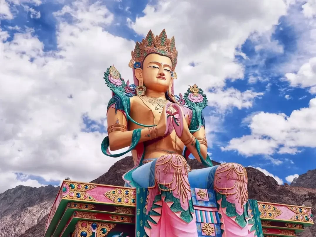 Majestic Maitreya Buddha statue Diskit Gompa vibrant colors blue sky mountain backdrop near Hunder Nubra Valley Ladakh monastery landmark camel safari tour package Leh spiritual adventure