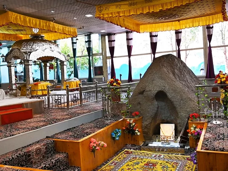 Gurdwara Pathar Sahib panoramic interior Leh Ladakh showing silver canopied Guru Granth Sahib yellow hangings Pathar miracle rock floral shrines wooden railings purple curtains carpets, dual shrine worship hall spiritual Ladakh tour package vista.
