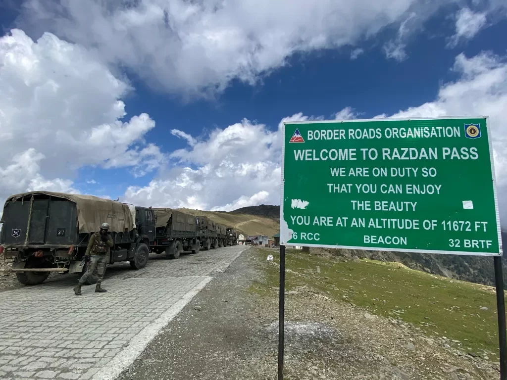 Welcome sign at Razdan Pass near Gurez during partly cloudy weather, featuring army trucks and mountains, perfect adventure Srinagar tour package. 
