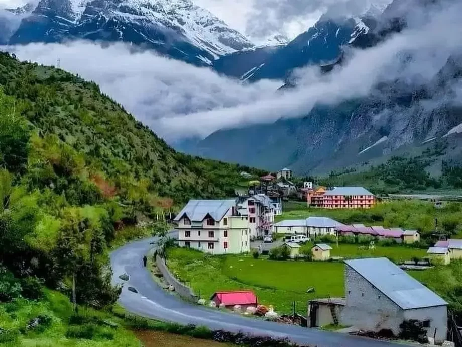 Colorful hotels and buildings in Jispa village Lahaul Spiti during misty morning, featuring snowy mountains, valley road, perfect Manali Leh tour package.
