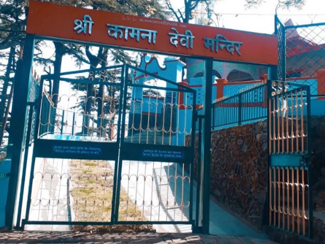 Kamna Devi Temple entrance gate in Shimla, Himachal Pradesh, featuring a turquoise-painted temple complex behind iron gates with a Hindi signboard, a popular spiritual site included in Himachal Pradesh tour packages.