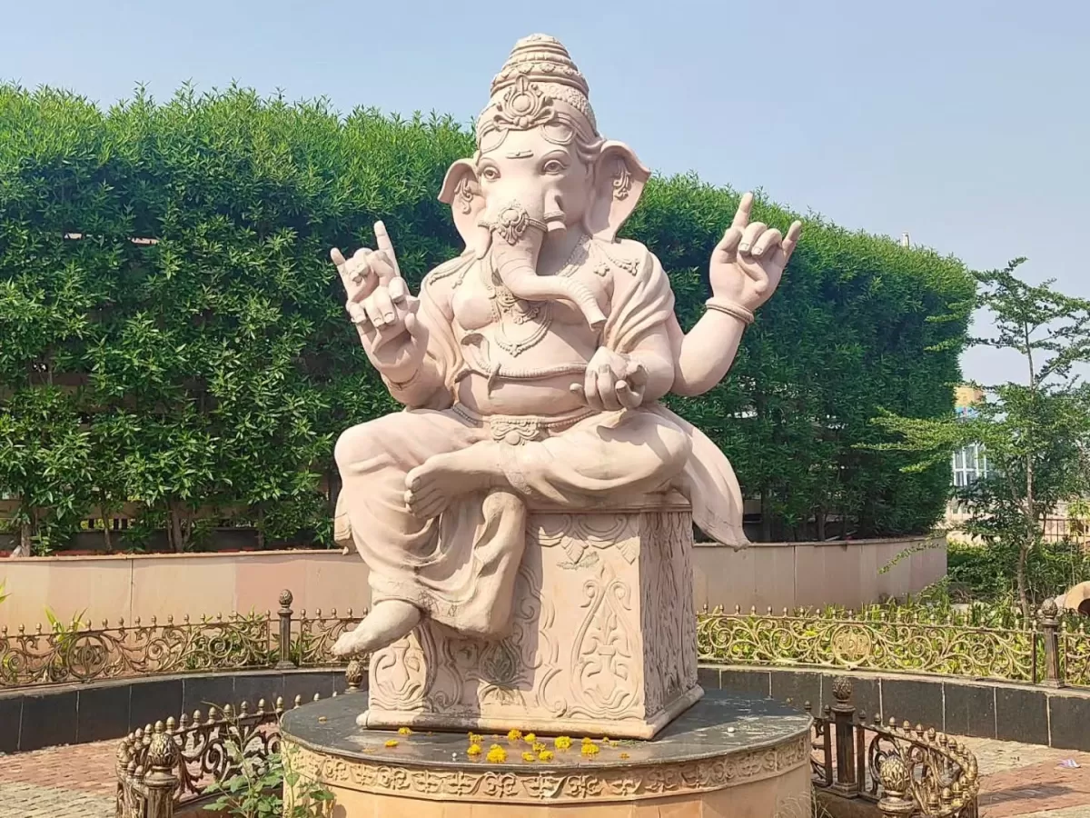 Pink Ganesha statue with rock gesture at Mahakal Lok Corridor Ujjain during clear daylight, featuring hedges railing, perfect spiritual Madhya Pradesh tour package.