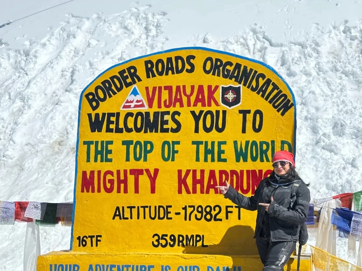 Khardungla Pass sign at Top of the World Ladakh during snowy winter, featuring BRO board prayer flags snow peaks, perfect adventure Ladakh tour package.