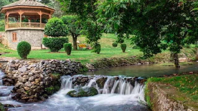 Kokernag Jammu Kashmir wooden gazebo garden trimmed bushes flowing stream pine trees lush greenery Jammu Kashmir tour packages.