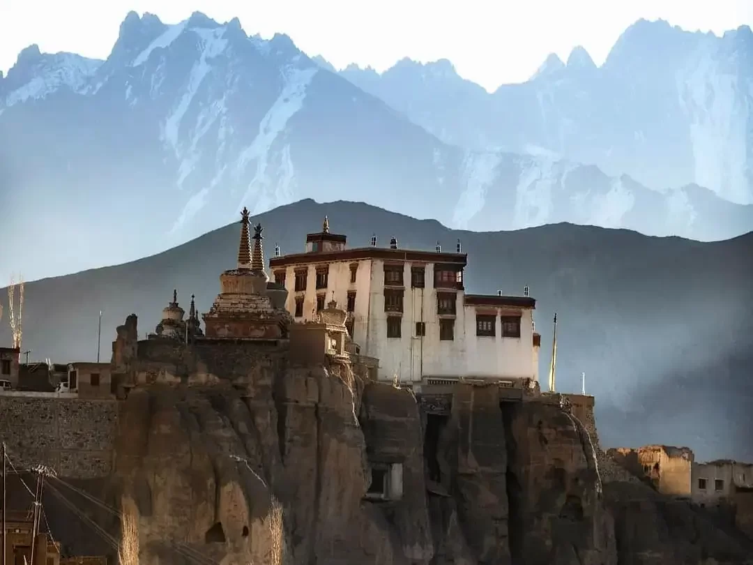 Lamayuru Gompa perched on cliffs in Ladakh at sunset, featuring white monastery buildings and snow-capped Himalayas, perfect Ladakh t.our package