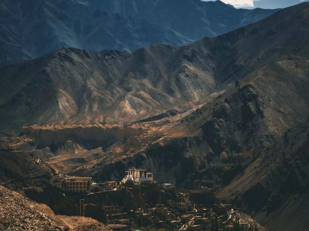Lamayuru Gompa nestled in moonscape valley of Ladakh at golden hour, featuring white monastery and rugged mountains, perfect Ladakh tour package