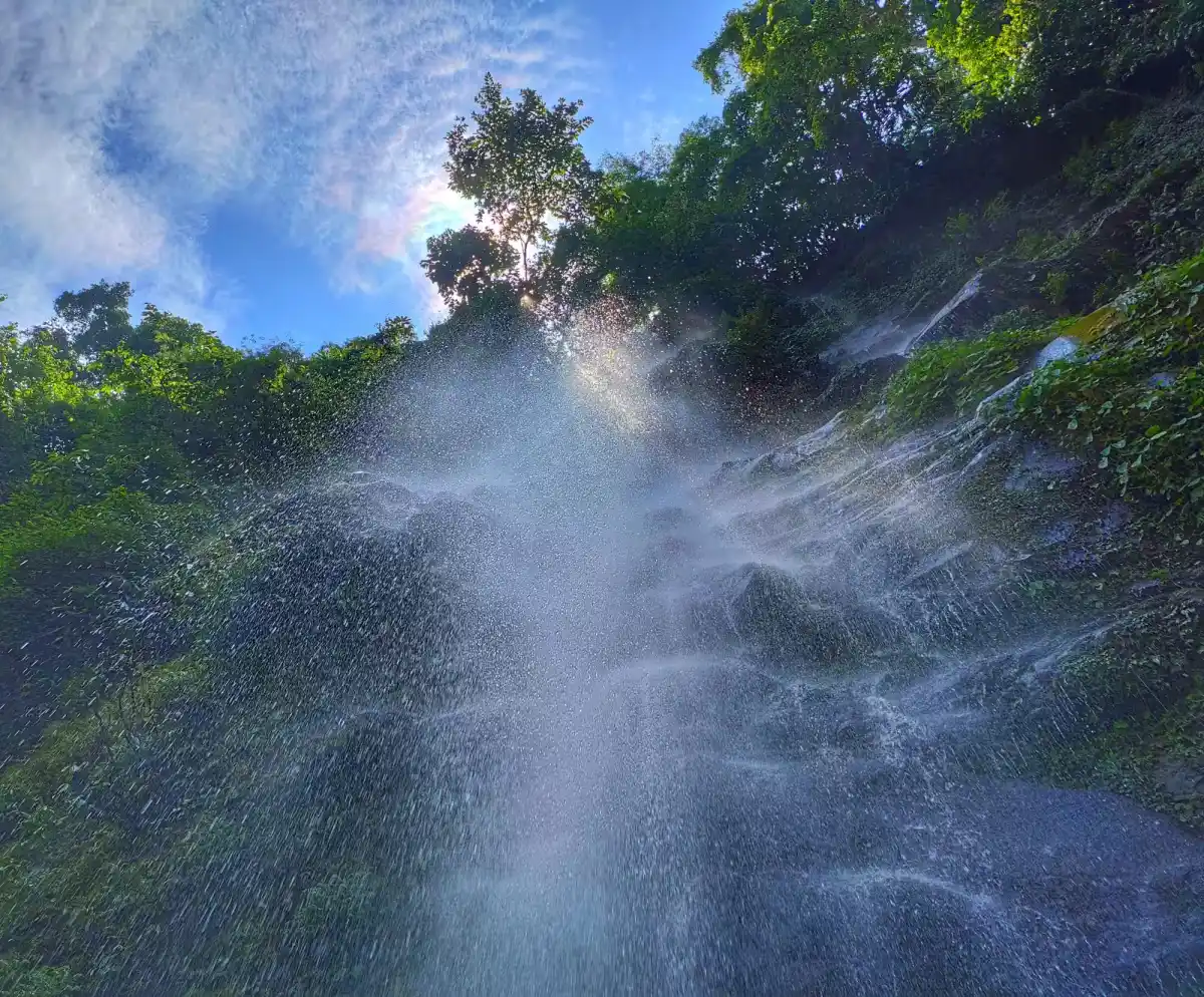 Sri Siganduru Chowdeshwari Temple near Sagara featuring cascading waterfall spray, rocky cliff face, and lush green forest canopy, perfect spiritual experience with Shimoga tour package.