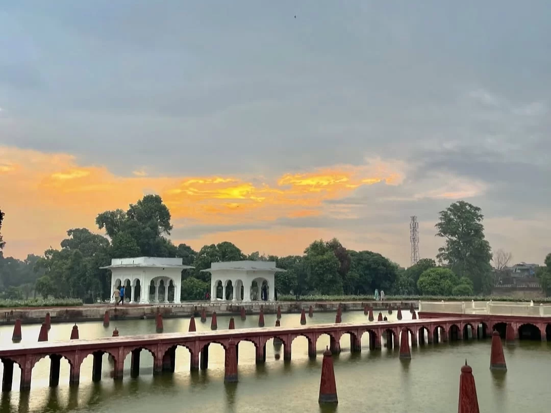 Shalimar Bagh pavilions at Nishat Garden Srinagar during sunset, featuring red bridges, lake reflections and trees, perfect romantic experience in Srinagar tour package.