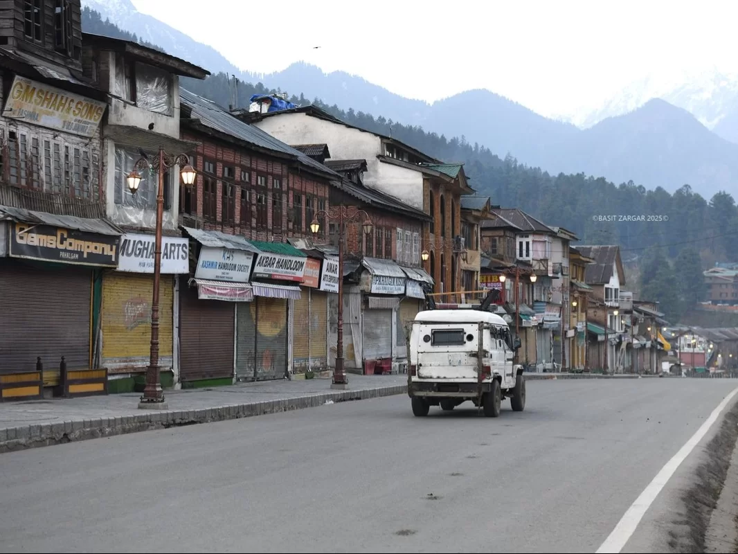 Pahalgam Main Market Kashmir wooden shops shutters colorful signs white jeep snowy Himalayan mountains Jammu Kashmir Kashmir tour packages. 