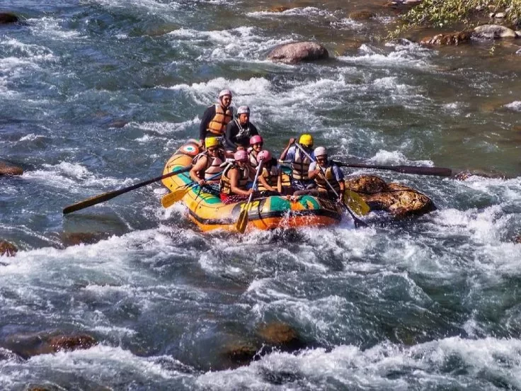 Pahalgam Lidder River rafting group tourists colorful raft paddling rapids rocky riverbank helmets lifejackets, Jammu Kashmir adventure tour packages. 