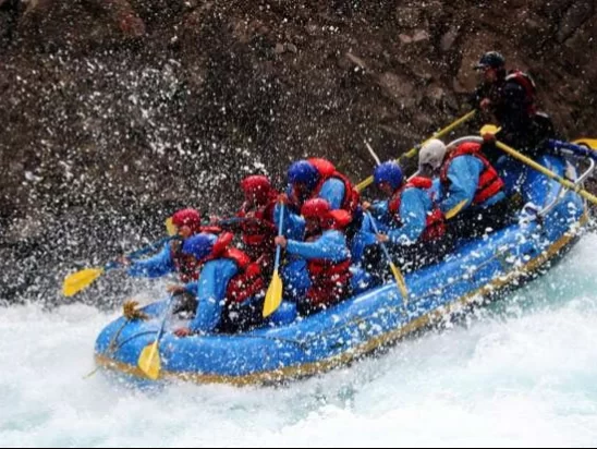 Pahalgam rafting adventure group rafters blue raft paddling rapids Lidder River rocky canyon splashes helmets lifejackets, Jammu Kashmir adventure tour packages. 