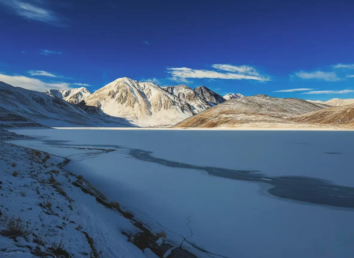 Frozen Pangong Lake at Pangong Tso Ladakh in winter, featuring snow capped mountains and icy reflections, perfect adventure Ladakh tour package.