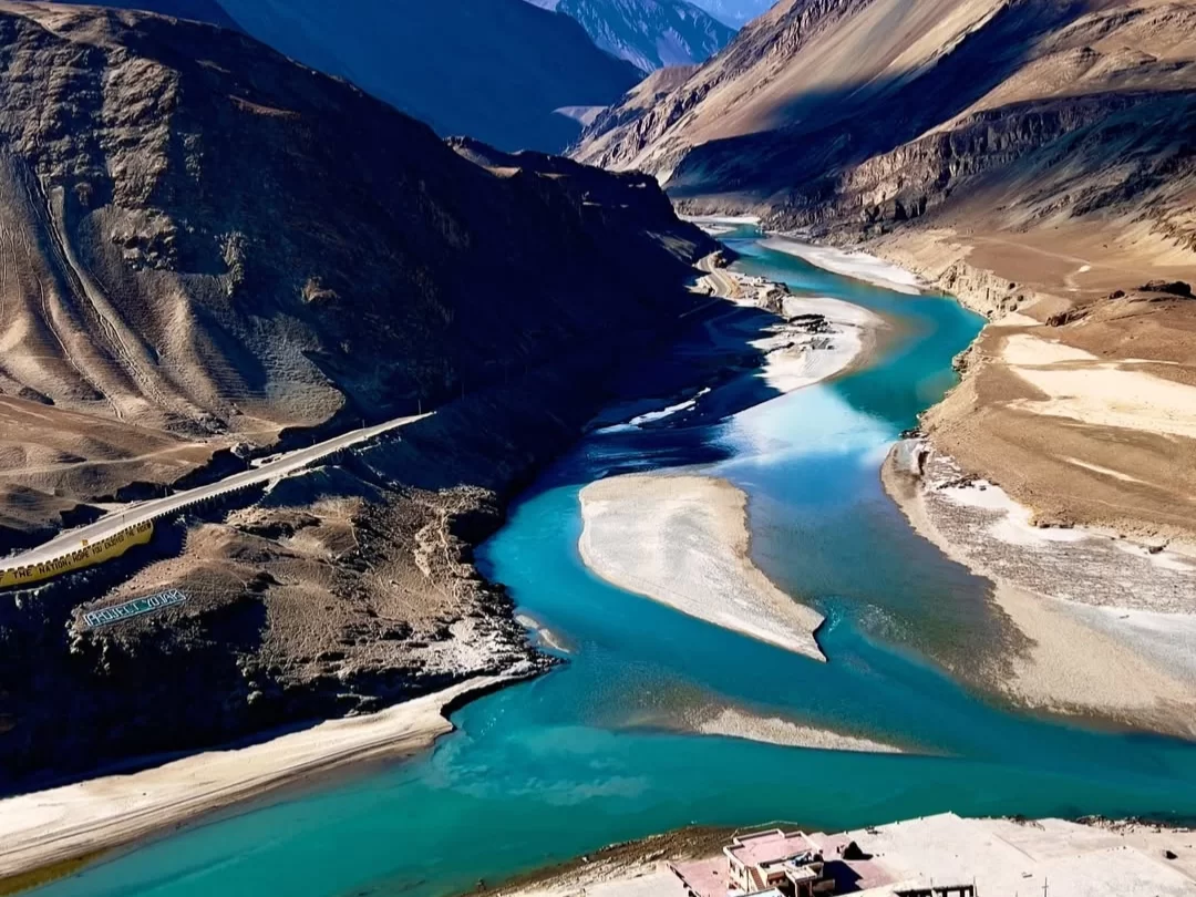 Sangam rivers at Leh Ladakh during sunny day, featuring turquoise waters mountain valley road sandbanks, perfect adventure Ladakh tour package.