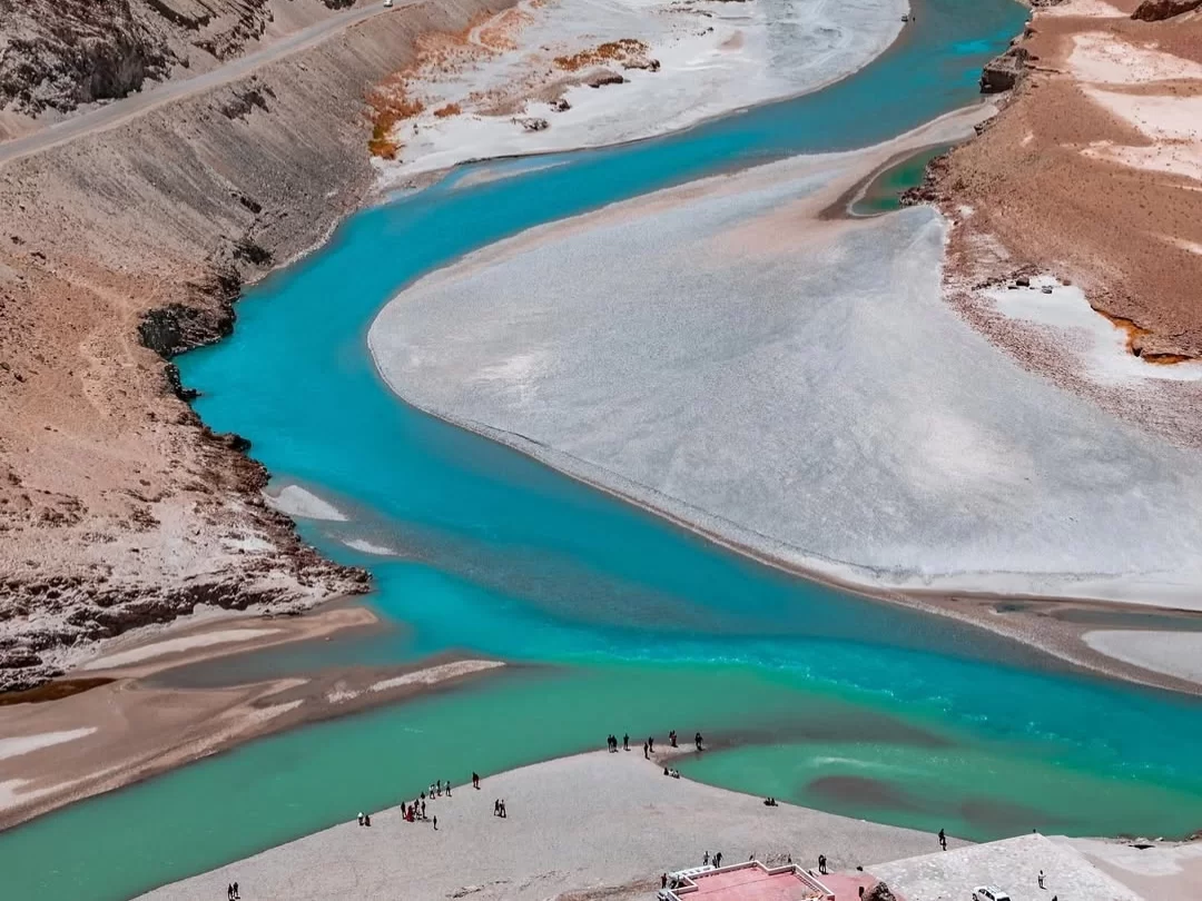 Sangam confluence at Leh Ladakh during sunny afternoon, featuring turquoise rivers sandbanks valley mountains travelers, perfect adventure Ladakh tour package.