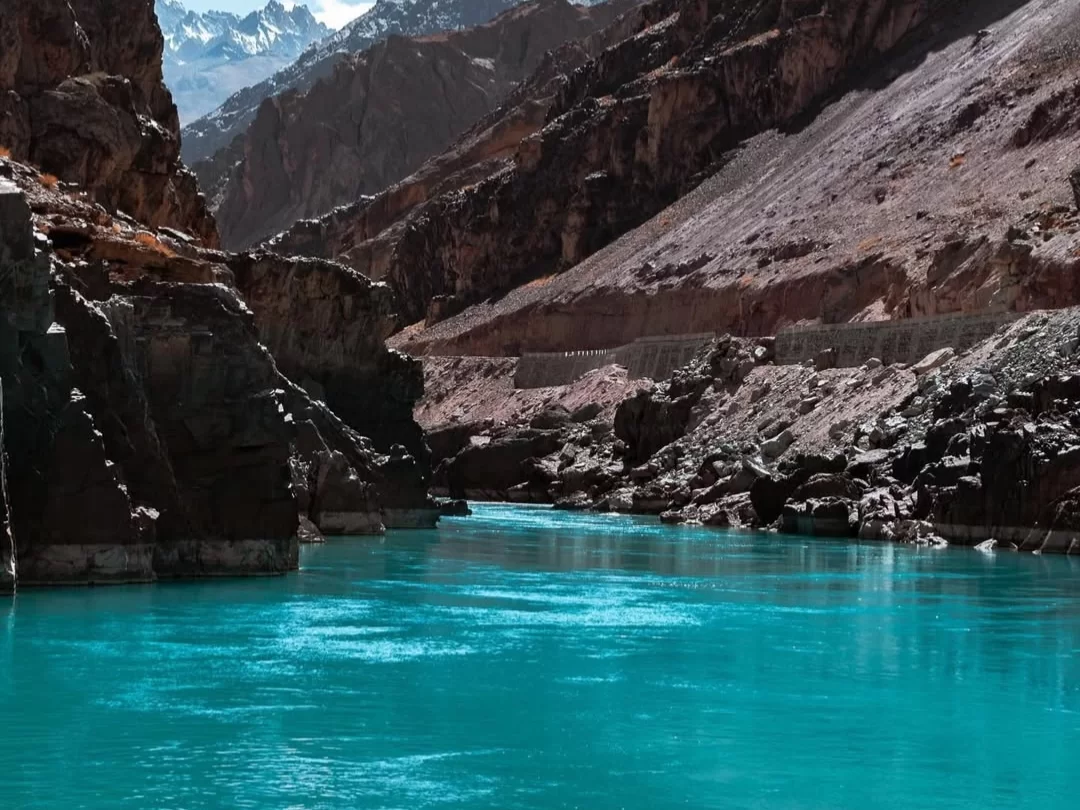 Indus river gorge at Sangam Leh Ladakh during sunny day, featuring turquoise waters rocky canyon snow peaks road, perfect adventure Ladakh tour package.