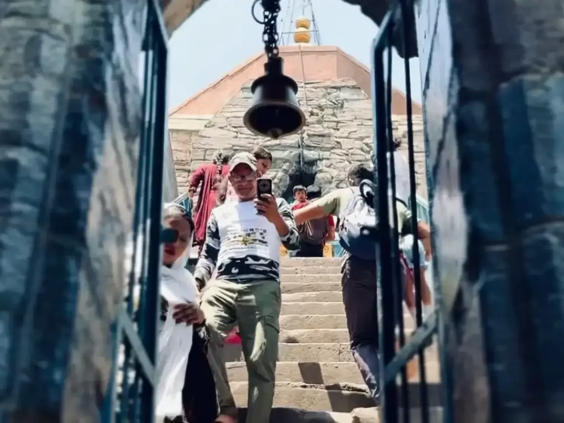 Shankracharya Temple Srinagar during sunny day Jammu Kashmir, featuring stone temple entrance saffron flag bell devotees stairs blue sky backdrop, perfect Jammu Kashmir tour packages. 