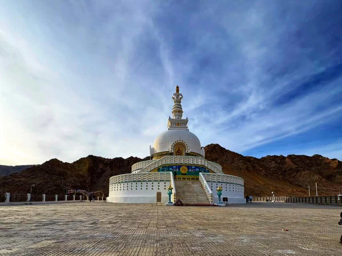 Shanti Stupa Leh panoramic view white stupa golden top blue skies Ladakh mountains plaza visitors, perfect Himalayas spiritual adventure tour package.