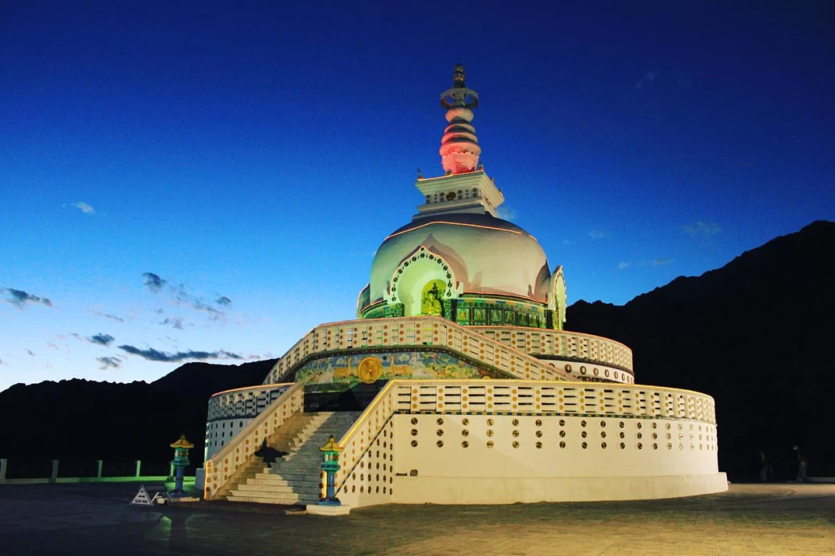 Shanti Stupa Leh night lights colorful dome spire green door blue base staircase Ladakh mountains starry sky, perfect Himalayas spiritual tour package.