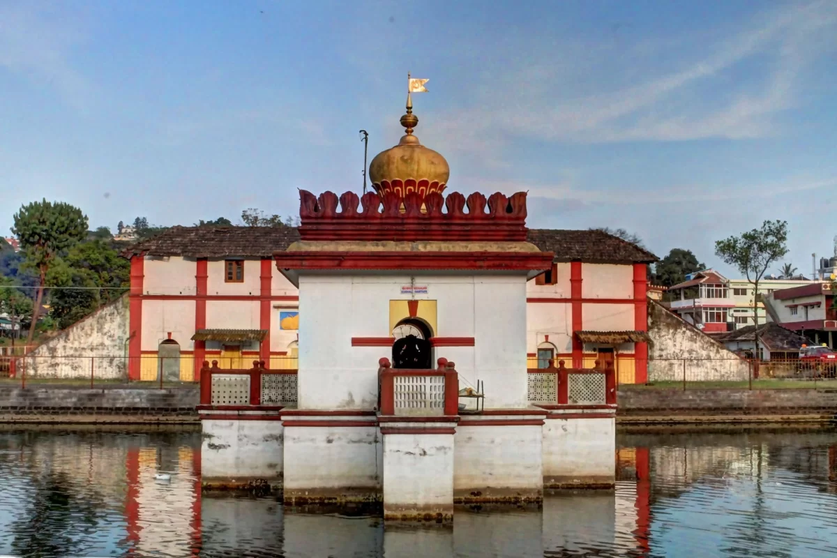 Shri Omkareshwara Temple at Madikeri during sunny day, featuring pond reflection, golden dome, red-white architecture, trees, perfect cultural experience Coorg tour packages.