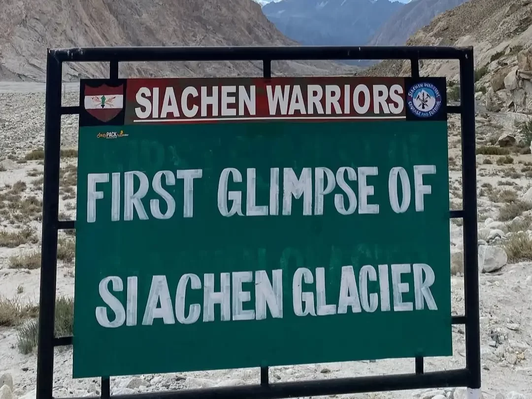 Siachen Warriors signboard at Siachen Base Camp in Ladakh during sunny day, featuring first glimpse glacier view, rocky valley, perfect adventure Siachen tour package.