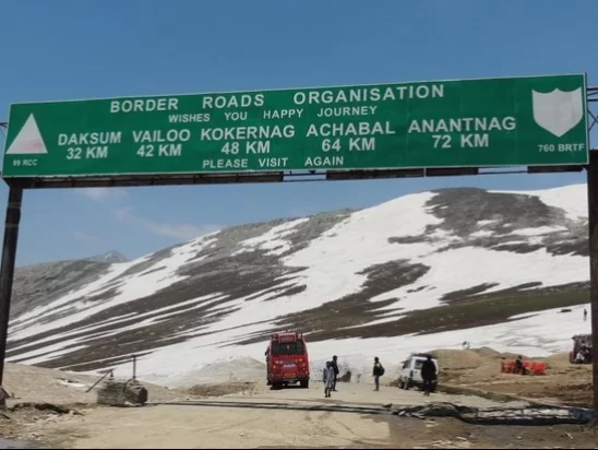 Sinthan Top BRO signboard amid snowy mountains showing distances to Daksum Valley 42km Kokernag 48km Achabal 72km Anantnag, perfect Kashmir adventure tour packages. 