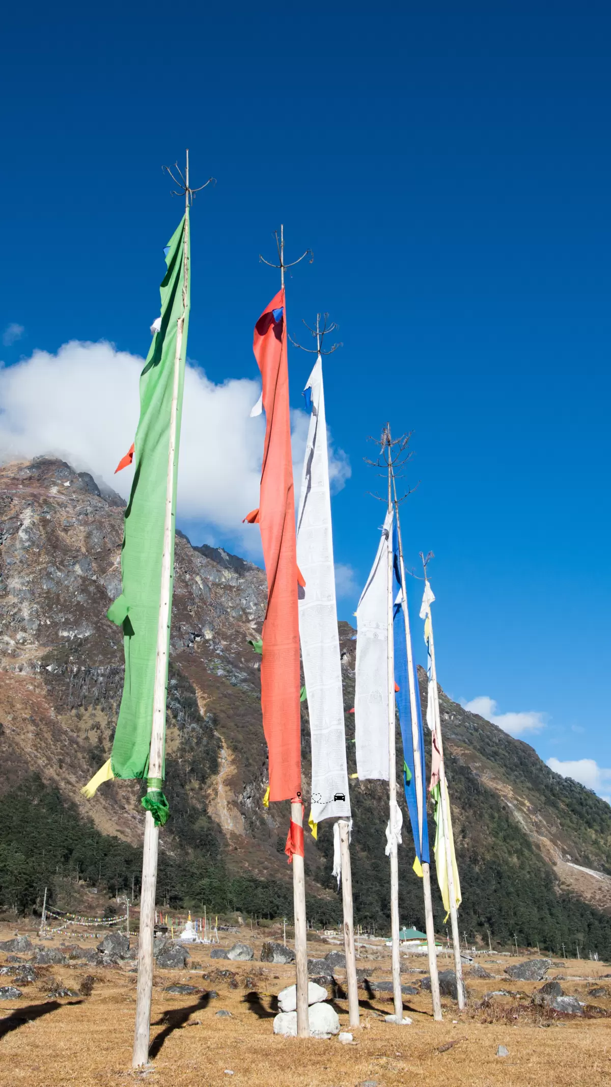 Colorful prayer flags in Yumthang Valley Sikkim fluttering against mountain backdrop and clear blue sky featured in Sikkim tour packages