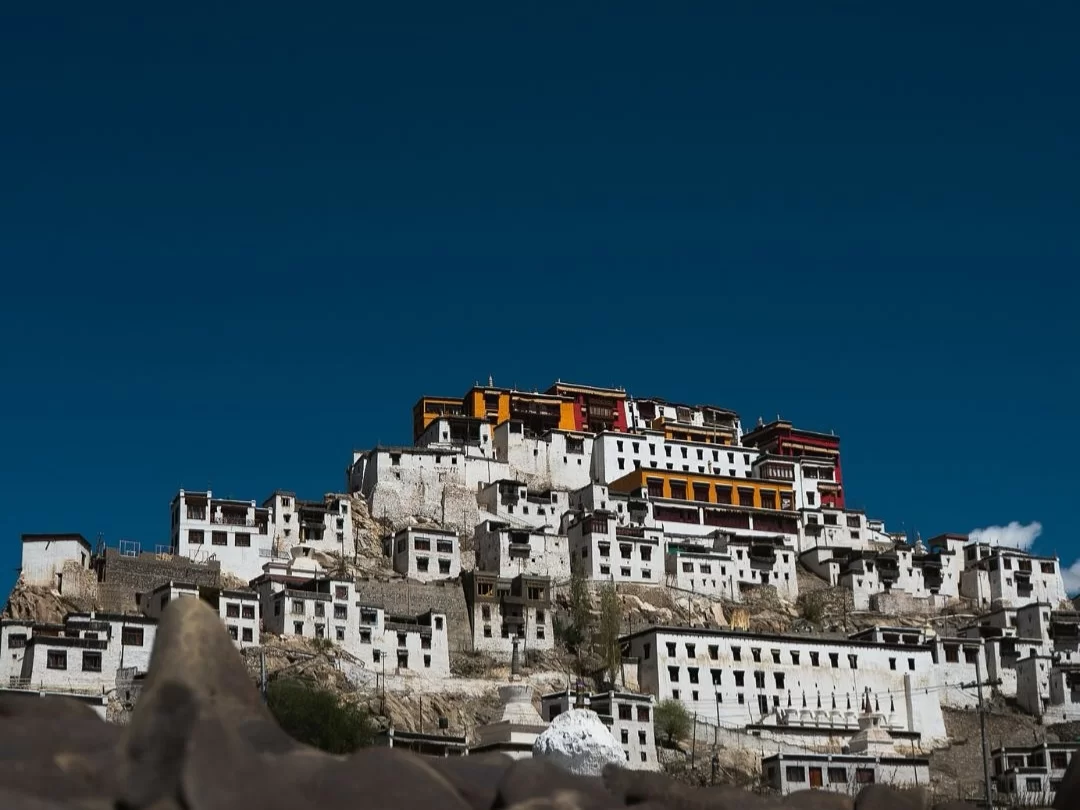 Towering Thiksey Gompa in Ladakh under clear blue sky, featuring layered white monasteries and colorful roofs, perfect Ladakh tour package.