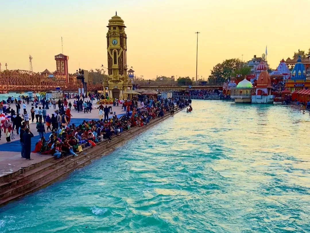 Har Ki Pauri Haridwar golden hour view of Hari ki Pairi clock tower crowded Ganga ghats devotees temples boats sunset sky, perfect aarti spiritual scene, Uttarakhand tour packages.