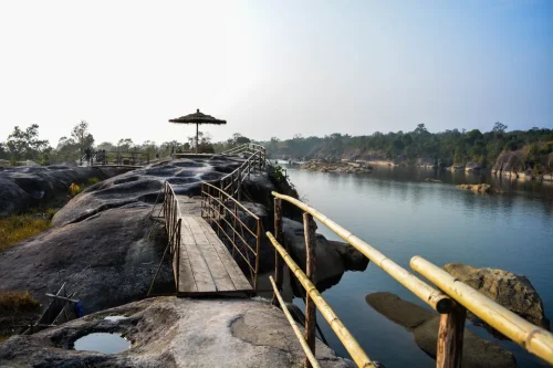 Umkhakoi Water Park in Mawlyngbna featuring wooden pathways, thatched umbrella, reservoir, and rock formations, perfect adventure experience with Meghalaya tour package.