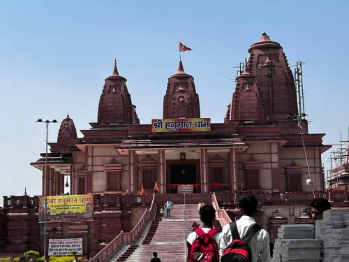 Hanuman Dham Temple at Jim Corbett Uttarakhand during sunny day, featuring red sandstone shikharas and temple signboard, perfect spiritual experience Uttarakhand tour package.