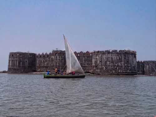 Murud-Janjira Fort Maharashtra Arabian Sea green boat white sail locals approaching massive black stone battlements sea water horizon blue sky; historic unconquered island coastal heritage photography package.