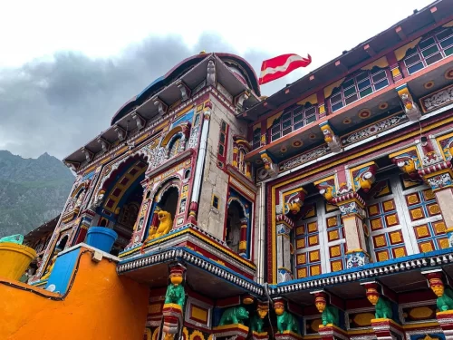Badrinath Temple Uttarakhand during cloudy weather, featuring colorful facade and Himalayan mountains, perfect spiritual experience Uttarakhand tour packages.