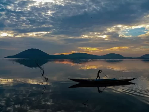 Chilika Lake Odisha silhouette fisherman boat sunset golden hour hills reflection tranquil waters, perfect Puri birdwatching boat safari tour package.