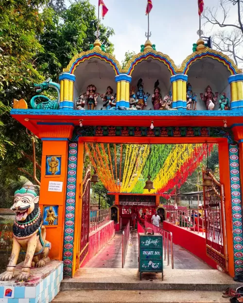 Colorful temple entrance at Taptapani Hot Spring in Odisha decorated with vibrant arches and flags featured in Odisha tour packages