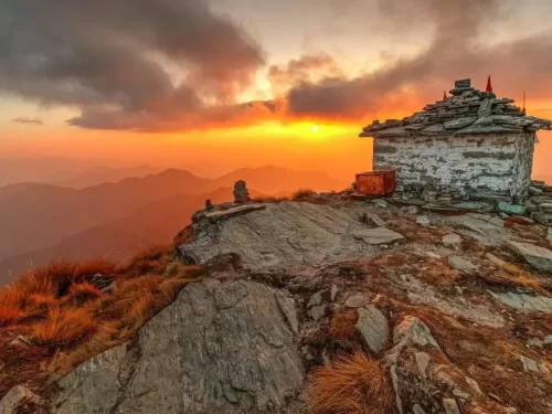 Stone shrine at Tungnath Temple during sunset glow, featuring rocky ridges & orange hues, perfect romantic experience Uttarakhand tour packages.