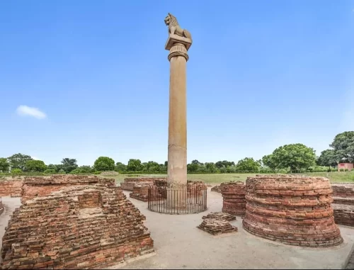 Ashoka Pillar with horse capital at Sanchi during clear afternoon, featuring monolithic shaft amid ancient ruins, perfect heritage experience in Madhya Pradesh tour package.