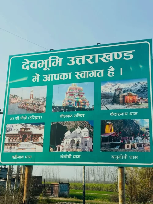 Welcome signboard reading Devbhoomi Uttarakhand featuring images of Char Dham temples including Kedarnath Badrinath Gangotri and Yamunotri promoting spiritual Uttarakhand tour packages