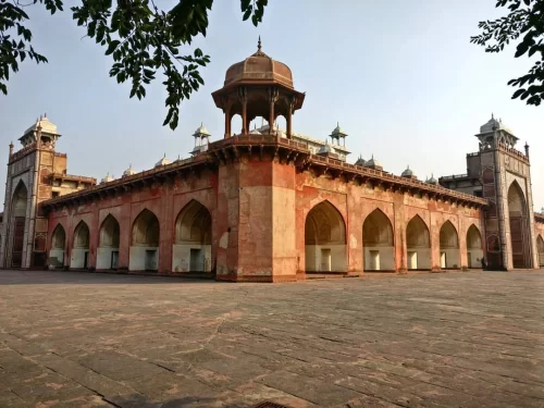 Akbar's Tomb Agra Uttar Pradesh red sandstone arches minarets domes palm trees courtyard blue sky Mughal architecture UNESCO heritage site, perfect Golden Triangle heritage tour package.