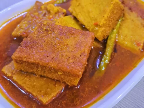 Aktori, a traditional Assamese dish made with soft gram-flour cakes simmered in a light, spiced curry with subtle earthy flavors.