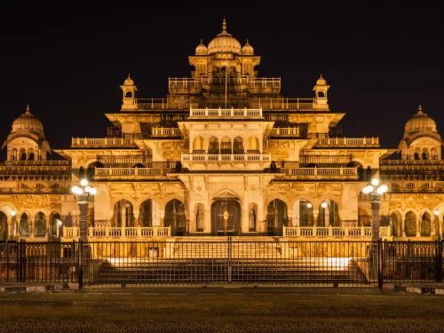 Albert Hall Museum in Jaipur at night illuminated in golden lights showcasing Indo-Saracenic architecture with domes, arches and railings, perfect Rajasthan tour package.