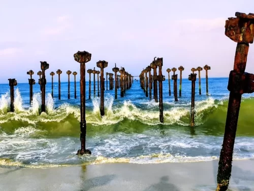 Alleppey Beach, Kerala India iconic old pier pillars in Arabian Sea with crashing waves and sandy shoreline.