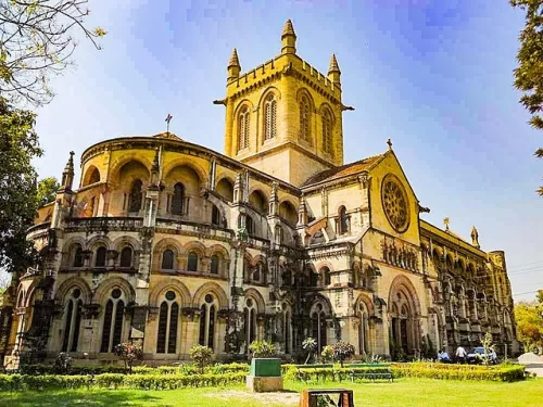 All Saints Cathedral sunny sky, Gothic yellow stone towers rose window arches trees lawns cars, perfect Uttar Pradesh tour package.