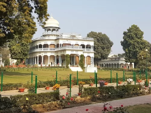 Anand Bhavan sunny sky, white mansion dome balconies lawns flowers trees fence, perfect Uttar Pradesh tour package.