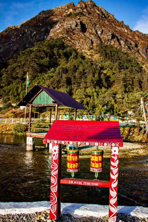 Prayer wheels near Madhuri Lake in Arunachal Pradesh with scenic mountains and riverside view featured in Arunachal Pradesh tour packages