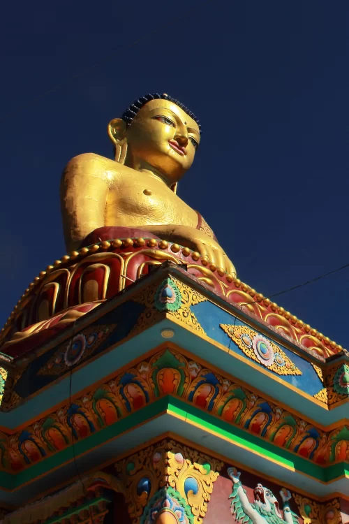 Golden Buddha statue at Tawang in Arunachal Pradesh with vibrant monastery architecture under clear blue sky featured in Arunachal Pradesh tour packages