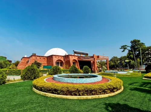 Assam State Zoo cum Botanical Garden entrance at Guwahati during sunny day, featuring dome building fountain greenery trees, perfect family experience Assam tour package.