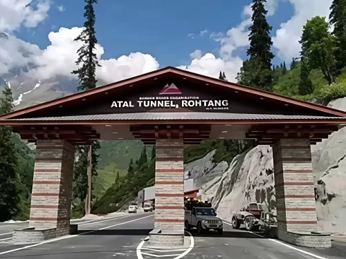 Atal Tunnel entrance at Rohtang Manali during clear skies, featuring wooden gate pine trees and vehicles, perfect adventure experience Himachal Pradesh tour package.
