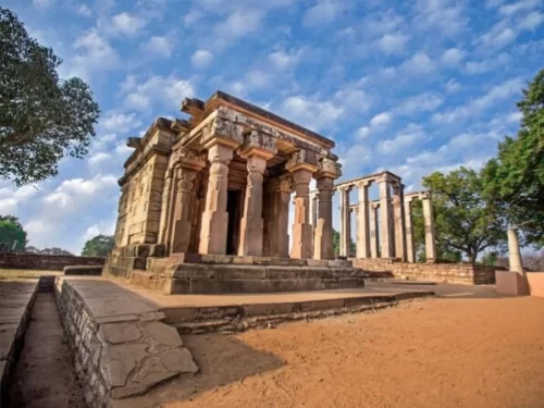 Ath Khamba Temple in Madhya Pradesh showcasing ancient stone pillars and detailed carvings under a dramatic sky, a historic site frequently explored through Madhya Pradesh tour packages.