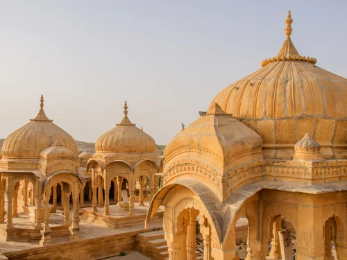 Bada Bagh Jaisalmer cluster of ornate yellow sandstone chhatris cenotaphs royal memorials intricate carvings golden hues, perfect Rajasthan heritage cultural tour packages. 