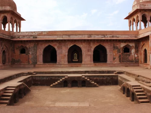 Baz Bahadur Palace courtyard at Gwalior Fort under clear skies, featuring domed pavilions and central stepwell, perfect heritage experience with Madhya Pradesh tour packages.